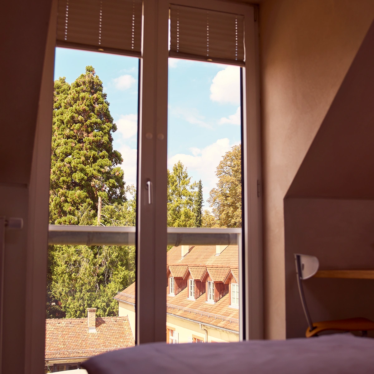 hotel-watthalden-watthaldenzimmer05 Blick in ein Watthaldenzimmer mit großem Fenster und Ausblick ins Grüne.